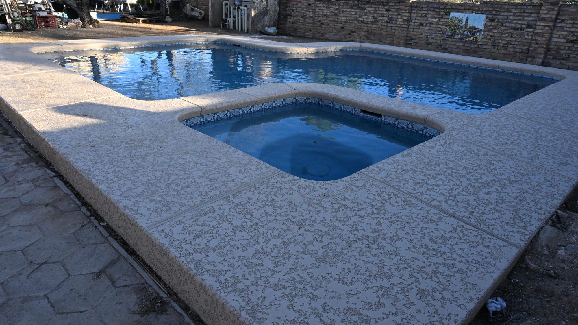 After: renovated pool with stamped concrete deck and raised spa